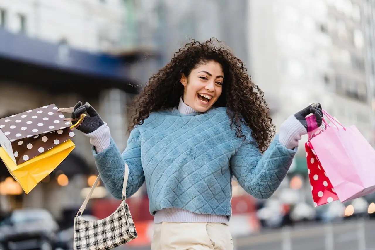 A woman smiling holding multiple shopping bags.